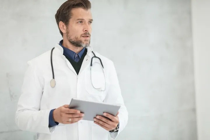 Farmacêutico de jaleco branco com tablet em ambiente clínico